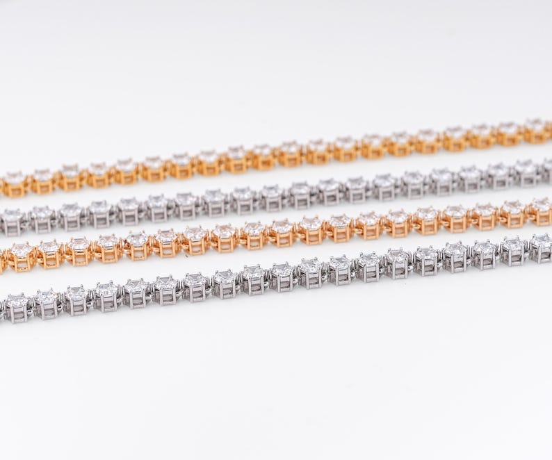 K&ouml;nnte beinhalten: Vier Diamant-Tennisarmb&auml;nder in Gold- und Silbert&ouml;nen werden vor einem wei&szlig;en Hintergrund gezeigt. Die Armb&auml;nder bestehen aus quadratisch geschliffenen Edelsteinen, die in einer durchgehenden Linie angeordnet sind und einen funkelnden und eleganten Look erzeugen.