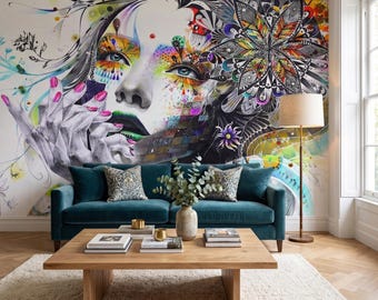 May include: A teal velvet sofa sits before a wall mural featuring a stylized face with vibrant, multicolored paint splatters and intricate mandala patterns. A wooden coffee table with books and a vase of greenery rests on a cream rug.