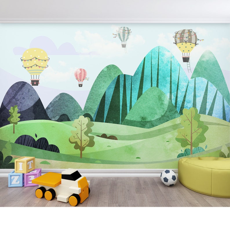 K&ouml;nnte beinhalten: Eine farbenfrohe Illustration einer gr&uuml;nen und blauen Berglandschaft mit Hei&szlig;luftballons, die dar&uuml;ber schweben. Die Szene ist im Aquarellstil gemalt und umfasst B&auml;ume und eine gr&uuml;ne Wiese.