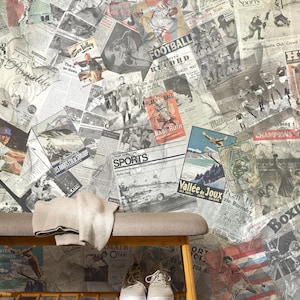 Könnte beinhalten: Eine Wand, bedeckt mit Vintage-Zeitungsartikeln und Sportplakaten, bildet den Hintergrund für eine Bank mit einem beigen Überwurf und einem Paar Turnschuhen. Die Poster zeigen Fußball-, Baseball- und Skithemen.