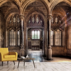 May include: An interior shot of a historic building with stone walls, arched ceilings, and large windows. A yellow armchair and a small table with a vase are in the foreground. The room has a classic, elegant design.