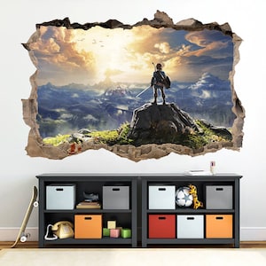 May include: A wall decal featuring a video game character standing on a cliff overlooking a vast, misty landscape. The character is wearing a blue tunic and holding a sword. The decal is designed to look like a hole in the wall, creating a 3D effect.