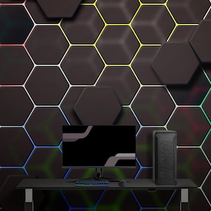 May include: A black computer setup with a monitor, keyboard, and tower on a black desk. The background features a hexagonal pattern with colourful LED lighting. The setup is designed for gaming or professional use.