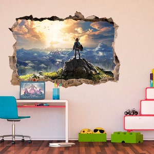 May include: A wall decal featuring a video game character standing on a cliff overlooking a mountain range. The decal is designed to look like a hole in the wall, creating a 3D effect.