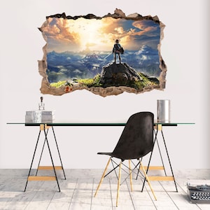 May include: A wall decal featuring a video game character standing on a mountaintop with a sunset in the background. The decal is designed to look like a hole in the wall, creating a 3D effect.