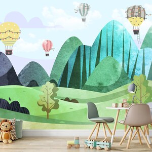 K&ouml;nnte beinhalten: Ein farbenfrohes Kinderzimmer mit einem Wandbild, das gr&uuml;ne und blaue Berge, einen hellblauen Himmel und gelbe, rosa und wei&szlig;e Hei&szlig;luftballons zeigt. Es gibt vier St&uuml;hle um einen kleinen Tisch mit Holzbeinen.