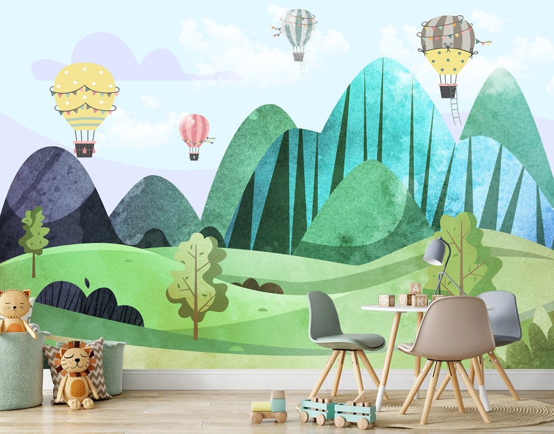 K&ouml;nnte beinhalten: Ein farbenfrohes Kinderzimmer mit einem Wandbild, das gr&uuml;ne und blaue Berge, einen hellblauen Himmel und gelbe, rosa und wei&szlig;e Hei&szlig;luftballons zeigt. Es gibt vier St&uuml;hle um einen kleinen Tisch mit Holzbeinen.
