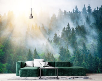 Pode incluir: Um sofá de veludo verde com almofadas brancas em frente a um mural de parede que representa uma floresta nebulosa com raios de sol atravessando as árvores.