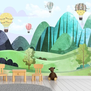K&ouml;nnte beinhalten: Eine farbenfrohe Illustration einer gr&uuml;nen und blauen Berglandschaft mit Hei&szlig;luftballons, die am Himmel schweben. Die Szene ist perfekt f&uuml;r ein Kinderzimmer oder einen Spielbereich.