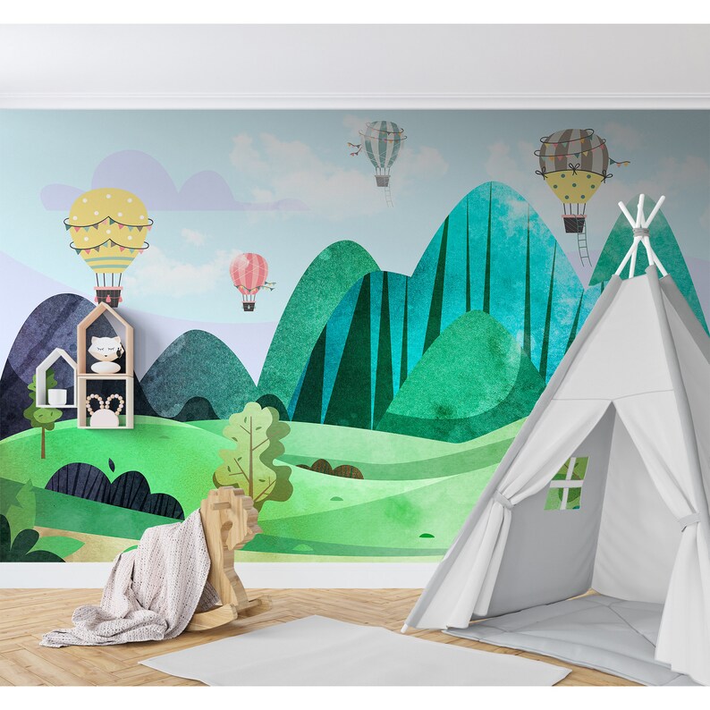 K&ouml;nnte beinhalten: Ein farbenfrohes Kinderzimmer-Wandbild mit einer gr&uuml;nen und blauen Berglandschaft mit Hei&szlig;luftballons. Das Wandbild ist an einer Wand mit einem wei&szlig;en Tipi-Zelt im Vordergrund angebracht.