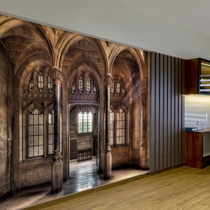 May include: A wall mural depicting a detailed, aged stone gothic cathedral interior with arched doorways and windows. The mural is installed in a room with wood flooring and a modern desk setup.