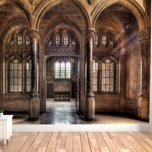 May include: An interior scene of a stone cathedral with arched doorways and large windows. The walls are a warm brown color, and the floor is made of wood. A small white nightstand with a clock and a plant sits in the foreground.