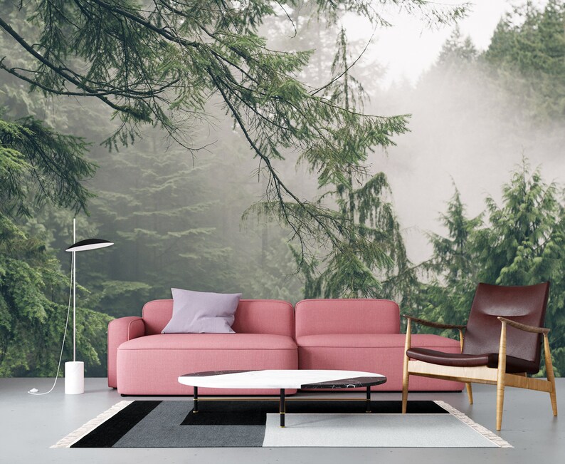 Pode incluir: Um sof&aacute; rosa e uma poltrona de couro marrom s&atilde;o posicionados em frente a um mural de parede que representa uma cena de floresta nebulosa. O sof&aacute; tem uma almofada de arremesso roxo claro e uma mesa de caf&eacute; com uma tampa de m&aacute;rmore branco fica entre os dois m&oacute;veis.
