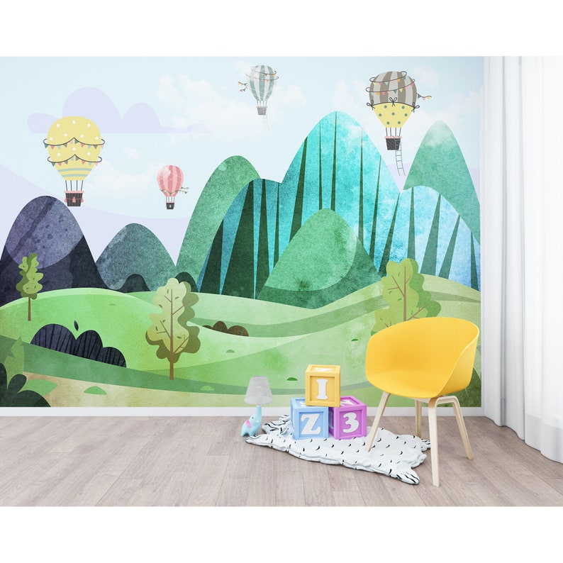 K&ouml;nnte beinhalten: Ein Aquarell-Wandbild mit einer gr&uuml;nen, blauen und violetten Berglandschaft, in der Hei&szlig;luftballons am Himmel schweben. Das Wandbild ist mit bunten Details verziert und eignet sich perfekt f&uuml;r ein Kinderzimmer.