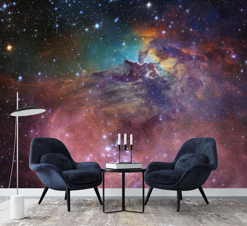 Puede incluir: Dos sillones azules con una mesa de caf&eacute; negra frente a un mural de pared que representa una nebulosa colorida con estrellas.