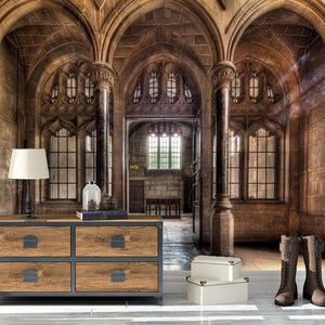 May include: An interior scene featuring a wooden dresser with four drawers, a black lamp, and a pair of brown boots. The room has arched doorways, large windows, and stone walls. Two white boxes are on the floor.