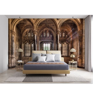 May include: A bedroom featuring a large mural of a gothic cathedral with arched windows and stone columns. The bed has a tan headboard, a gray duvet, and several pillows. Two gold bedside tables with lamps flank the bed, and a patterned rug is on the floor.
