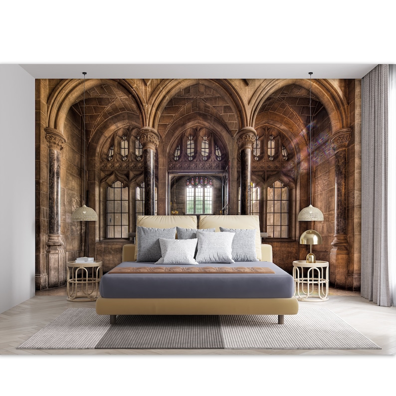 May include: A bedroom featuring a large mural of a gothic cathedral with arched windows and stone columns. The bed has a tan headboard, a gray duvet, and several pillows. Two gold bedside tables with lamps flank the bed, and a patterned rug is on the floor.