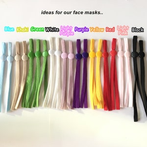 Könnte beinhalten: Eine Auswahl an Farben von elastischem Band mit Kunststoff-Schiebereglern. Die Farben umfassen Blau, Khaki, Grün, Weiß, Helllila, Lila, Gelb, Rot, Hellrosa und Schwarz.