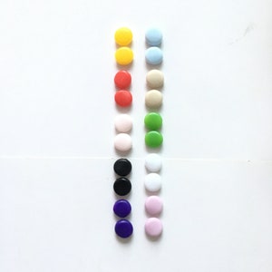 May include: Two rows of colourful round buttons, including yellow, blue, red, green, white, black, purple, and pink.