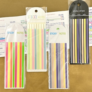 May include: Four sets of thin, rectangular sticky notes and sticky strips in clear plastic packaging. The sets feature various color palettes including neon pink, orange, yellow, green, pastel tones, and dark shades, all labeled with Sticky Notes or Sticky Strips.