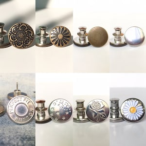 Könnte beinhalten: Sortiment an Metall-Jeansknöpfen mit verschiedenen Designs, darunter ein Blumenmuster, ein Sternmuster, eine Rose und eine Gänseblümchen. Die Knöpfe sind silber und goldfarben und haben einen Metallstift zum Anbringen an Kleidung.