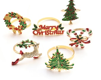 Puede incluir: Juego de seis anillos para servilletas de Navidad en tono dorado. Los anillos presentan varios diseños, incluyendo un árbol de Navidad, un reno, un bastón de caramelo, una corona y las palabras "Feliz Navidad".