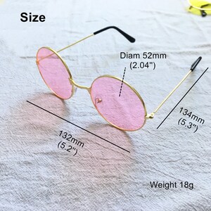 May include: Gold-rimmed round sunglasses with pink lenses. The sunglasses measure 5.2 inches wide and 5.3 inches long. The lenses are 2.04 inches in diameter. The sunglasses weigh 18 grams.