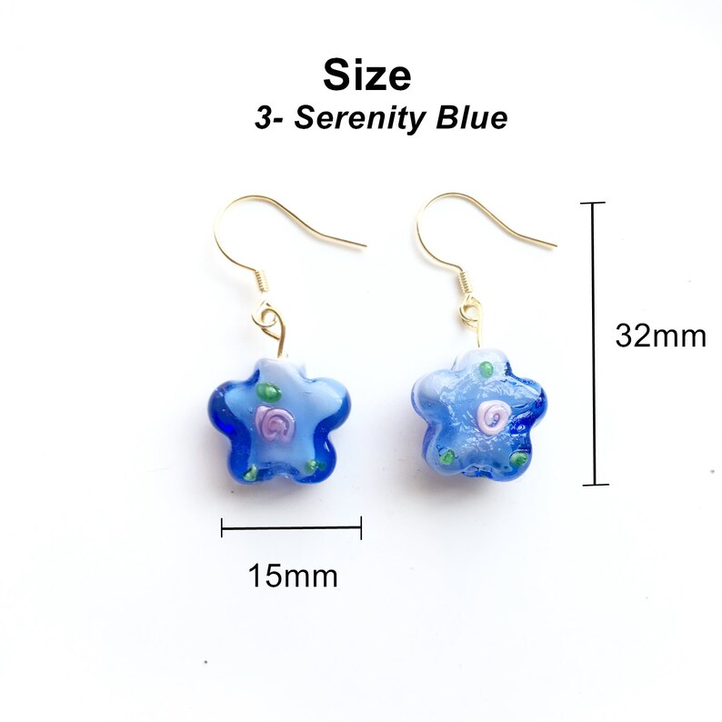 May include: A pair of blue star-shaped earrings with a white and pink floral design. The earrings are 32mm long and 15mm wide. Size: 3 - Serenity Blue.