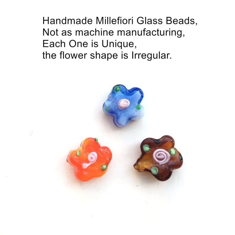 May include: Three handmade millefiori glass beads in the shape of flowers. The beads are blue, orange, and brown with white and green accents. Each bead has a unique, irregular shape.