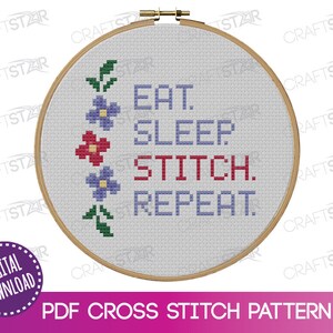 May include: A cross stitch pattern featuring the text "Eat. Sleep. Stitch. Repeat." in blue and red lettering. The text is surrounded by a border of green leaves and purple flowers.