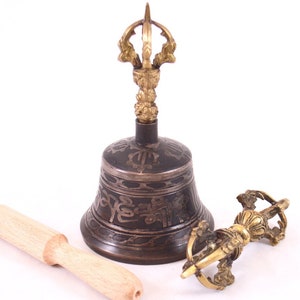 May include: A Tibetan singing bowl with a brass handle and a wooden striker. The bowl is decorated with intricate carvings and has a dark brown finish.