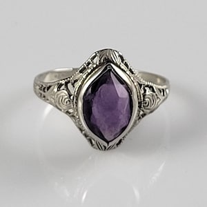 May include: A silver ring with an amethyst gemstone set in a filigree design.
