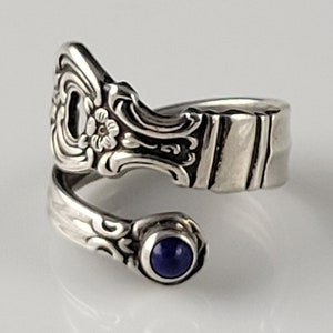 May include: A silver ring made from a vintage spoon with a blue gemstone set in the band.