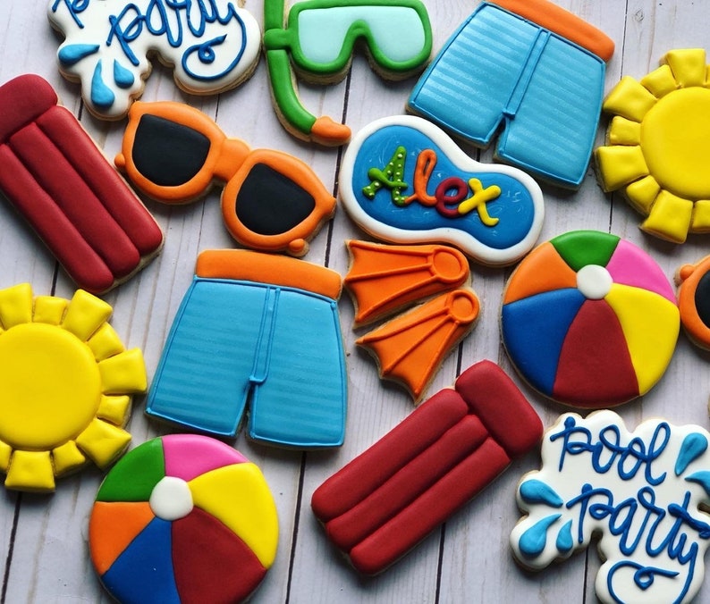 May include: A set of ten decorated sugar cookies with a pool party theme. The cookies are decorated with various summer-themed designs, including a pool float, a beach ball, a pair of sunglasses, a pair of swim trunks, a diving mask, a sun, and a sign that says "Pool Party".