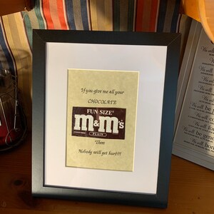 May include: A framed print with a brown and white M&M's candy wrapper. The text reads "If you give me all your CHOCOLATE FUN SIZE m&m's PLAIN Then Nobody will get hurt!!!"