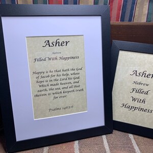 May include: Two framed prints with the name Asher in black script. The larger print has the Hebrew word for Asher and the meaning "Filled With Happiness". The smaller print has the same text but is smaller. Both prints have a parchment-like background.
