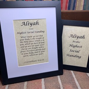May include: Two framed prints with the name "Aliyah" in cursive script. The larger print has the meaning of the name in Arabic, "Highest Social Standing", and a quote from 1 Corinthians 6:19-20. The smaller print has the meaning of the name in Arabic, "Highest Social Standing".