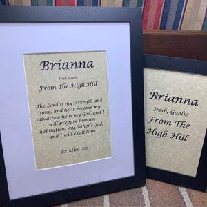 May include: Two framed prints with a white background and black frames. The prints feature the name Brianna in black text with the meaning "From The High Hill" in black text. The print on the left also includes a Bible verse from Exodus 15:2.