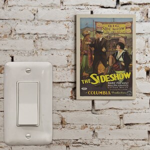 May include: Vintage movie poster for "The Sideshow" starring Marie Prevost, Ralph Graves, and Little Billy. The poster features a colorful circus tent and performers in costumes. It is a Columbia Production.