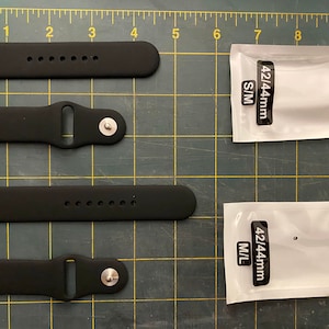 May include: Four black silicone watch bands with different sizes, two packages of watch bands labeled "42/44mm S/M" and "42/44mm M/L" on a black and white grid.
