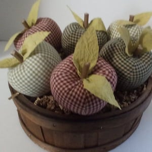 May include: A wooden basket filled with six fabric apples. The apples are in a variety of green and red plaid patterns with green leaves.