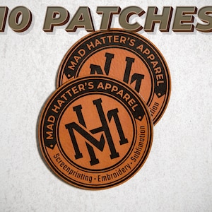 May include: Ten brown leather patches with the text "Mad Hatter's Apparel" and a monogram logo in black. The patches are round and have a stitched border.