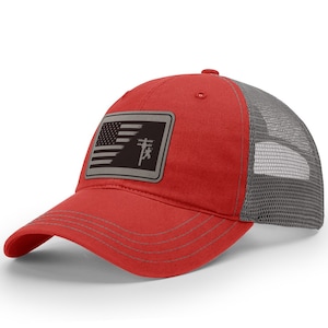 May include: Red and gray trucker hat with a patch featuring an American flag and a silhouette of a lineman on a power pole.