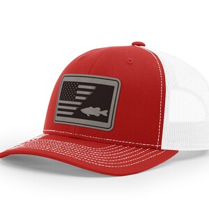 May include: Red and white trucker hat with a gray patch featuring an American flag and a fish silhouette.