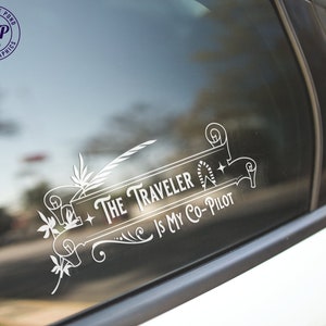May include: White vinyl decal with a decorative scroll design and the text "The Traveler is My Co-Pilot".