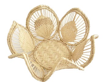 May include: A woven basket shaped like a flower with a light brown color. The basket is made of natural materials and has a unique design.