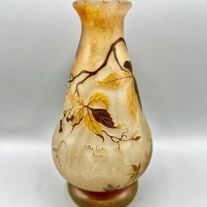 May include: A pale yellow glass vase with a pearlescent finish and a floral design in shades of brown and gold. The vase is signed "ADELLOTTE NANCY".