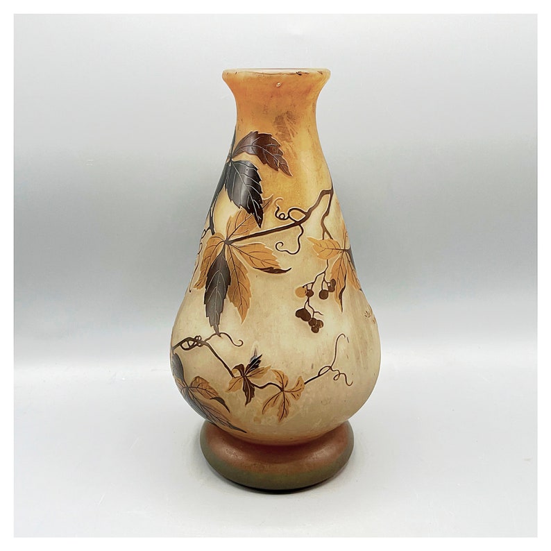 May include: A vintage glass vase with a pearlescent finish and a floral design in shades of brown and gold. The vase has a wide base and a narrow neck.