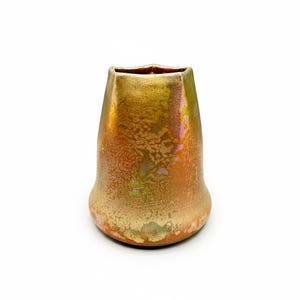 May include: A ceramic vase with a flared base and a tapered, slightly angular opening. The surface features a metallic, iridescent glaze with mottled textures in shades of gold, bronze, and copper, creating a reflective and multi-toned appearance.